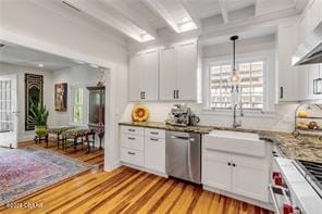 kitchen featuring white cabinets, beam ceiling, light hardwood / wood-style flooring, and stainless steel dishwasher