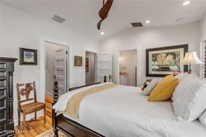 bedroom with wood-type flooring and vaulted ceiling