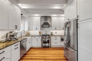 kitchen featuring white cabinets, stainless steel appliances, and wall chimney exhaust hood