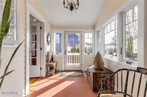 sunroom featuring an inviting chandelier and vaulted ceiling