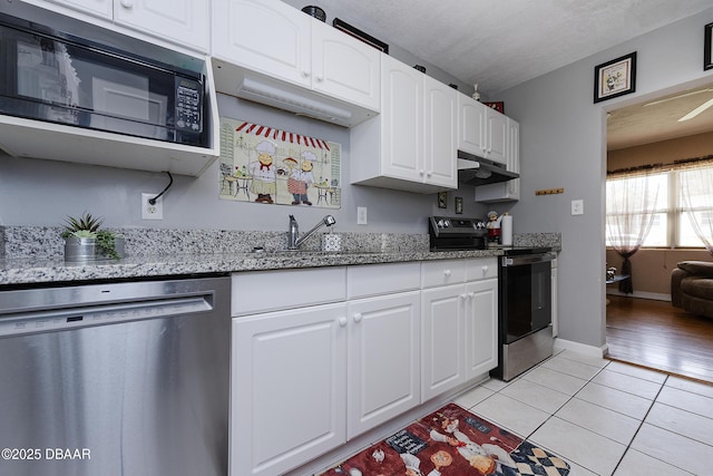 kitchen featuring stone counters, appliances with stainless steel finishes, white cabinetry, sink, and light tile patterned floors