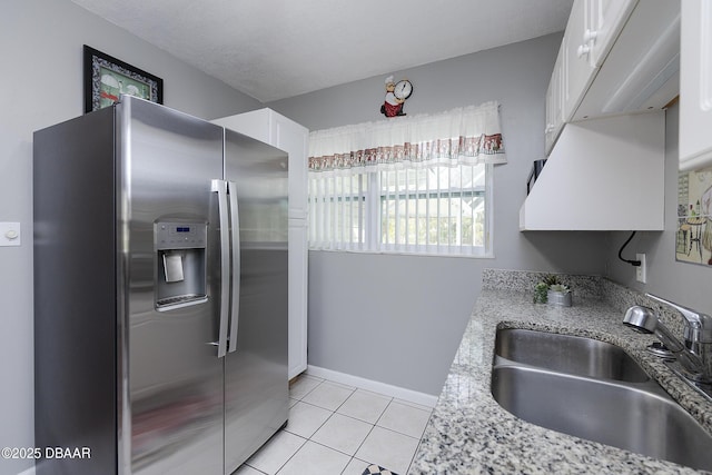 kitchen featuring light tile patterned flooring, sink, white cabinets, stainless steel refrigerator with ice dispenser, and light stone countertops