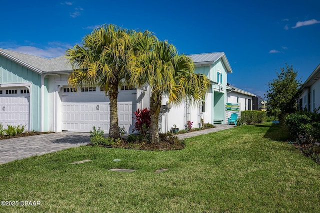 view of side of home featuring a garage, decorative driveway, and a yard