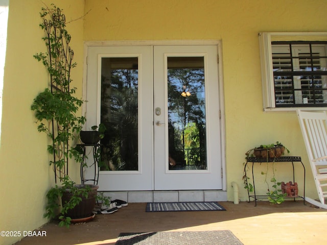 view of exterior entry featuring french doors and stucco siding