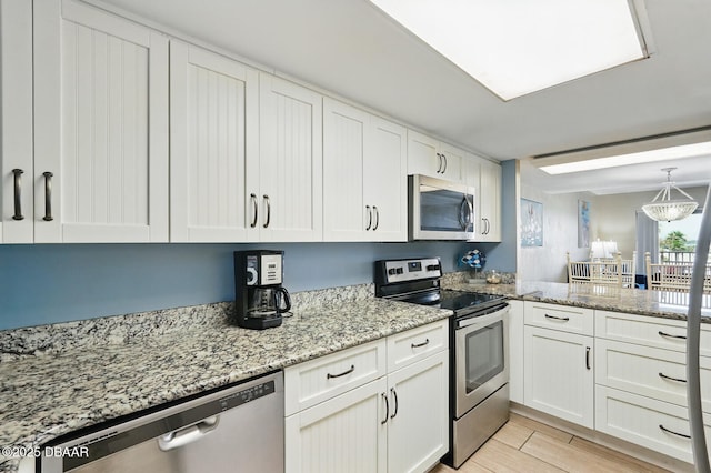 2626 S Atlantic Ave Unit 505, Daytona Beach, FL 32118 - kitchen featuring appliances with stainless steel finishes, white cabinets, light stone counters, and a peninsula