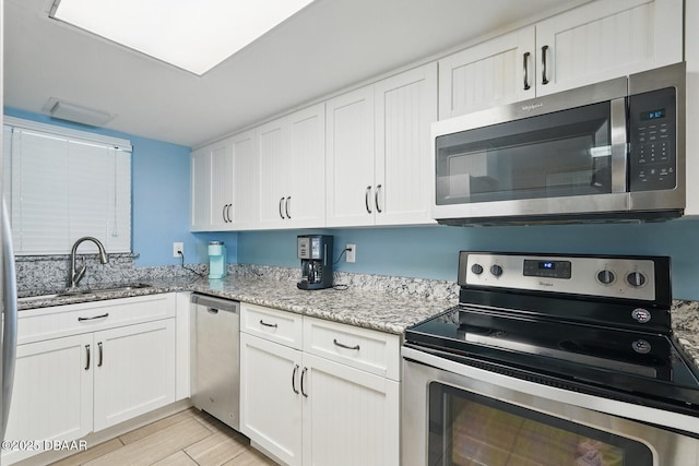 2626 S Atlantic Ave Unit 505, Daytona Beach, FL 32118 - kitchen featuring stainless steel appliances, a sink, white cabinetry, and light stone countertops