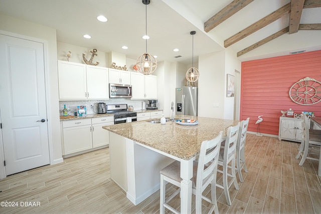 kitchen featuring light stone countertops, an island with sink, pendant lighting, white cabinets, and appliances with stainless steel finishes