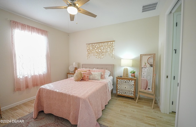 bedroom with ceiling fan with notable chandelier and light hardwood / wood-style flooring