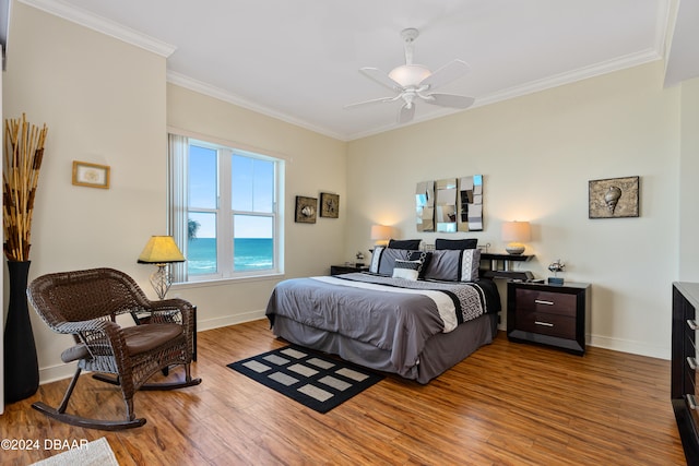 bedroom with ceiling fan, crown molding, a water view, and wood-type flooring