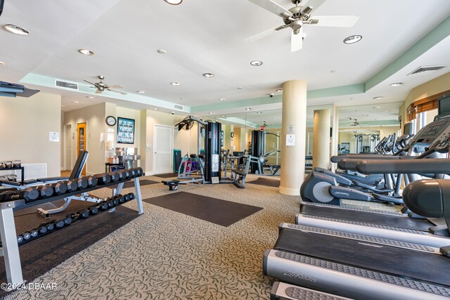 gym with a tray ceiling and carpet