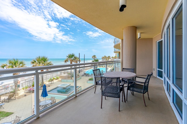 balcony with a jacuzzi, a water view, and a view of the beach