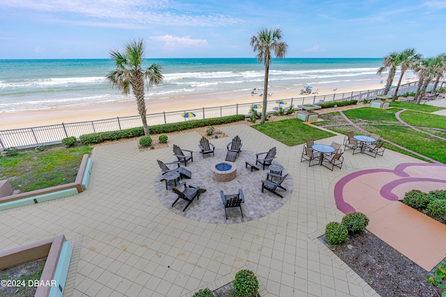 view of patio with a fire pit, a water view, and a view of the beach