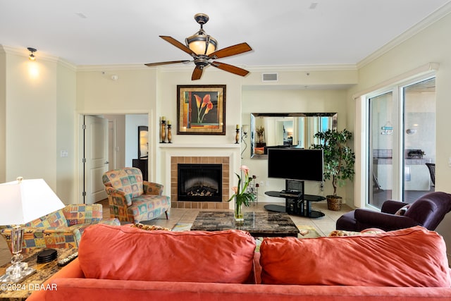 living room with a tiled fireplace, crown molding, and ceiling fan