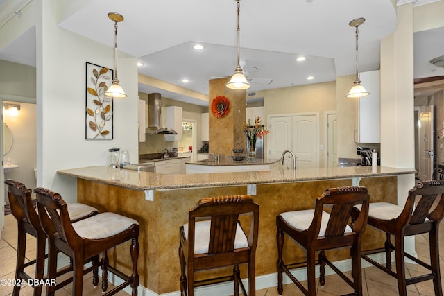 1925 S Atlantic Ave Unit 205, Daytona Beach Shores, FL 32118 - kitchen featuring wall chimney exhaust hood, a peninsula, a sink, light stone counters, and recessed lighting