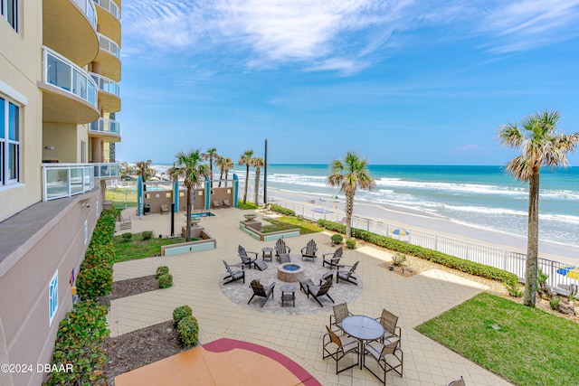 view of patio featuring a view of the beach, a water view, and an outdoor fire pit