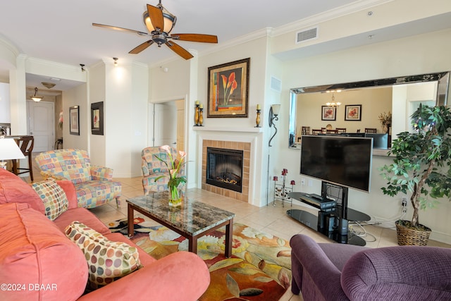 living room featuring a fireplace, light tile patterned floors, ceiling fan with notable chandelier, and ornamental molding