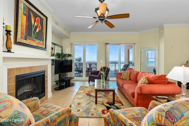 living room with a tile fireplace, light tile patterned floors, ceiling fan, and crown molding