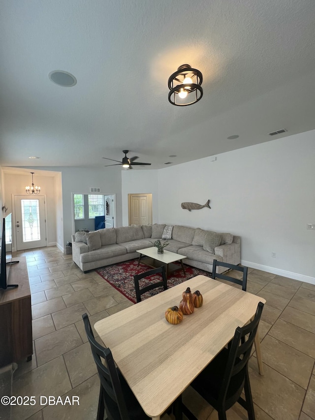 dining space featuring tile patterned flooring, ceiling fan with notable chandelier, and a textured ceiling