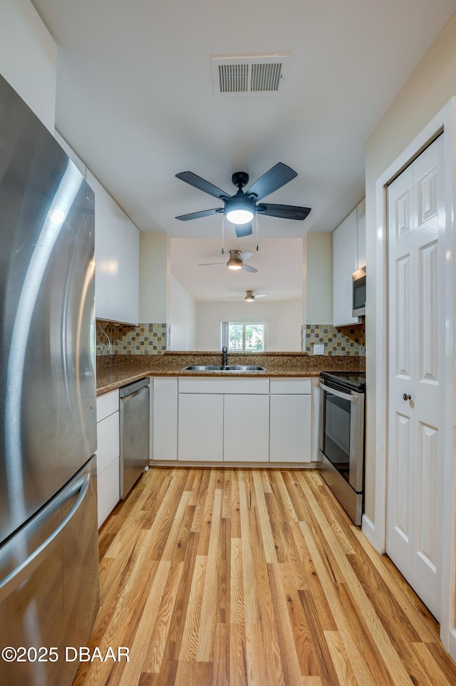 66 Rivers Edge Ln Unit 66, Palm Coast, FL 32137 - kitchen with appliances with stainless steel finishes, white cabinetry, decorative backsplash, and dark countertops