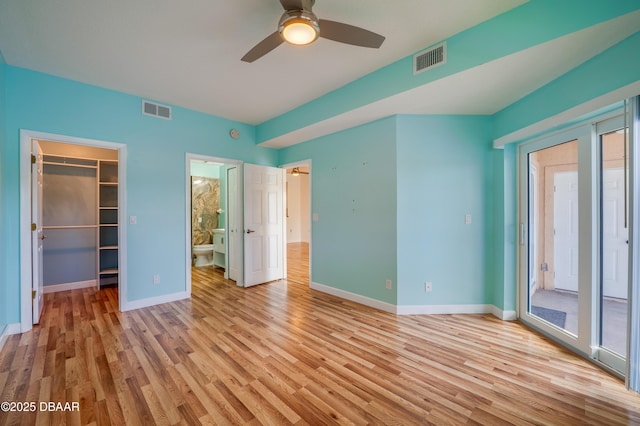 66 Rivers Edge Ln Unit 66, Palm Coast, FL 32137 - unfurnished bedroom with light wood-type flooring, a walk in closet, access to outside, a ceiling fan, and connected bathroom