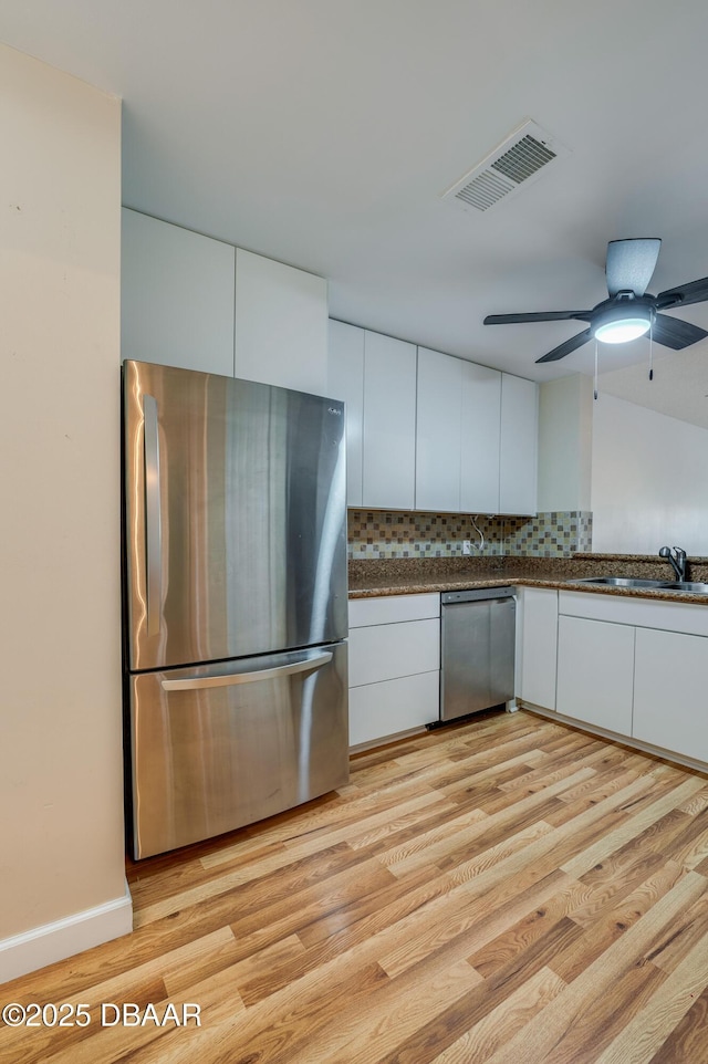 66 Rivers Edge Ln Unit 66, Palm Coast, FL 32137 - kitchen with appliances with stainless steel finishes, white cabinets, tasteful backsplash, light wood-style floors, and modern cabinets