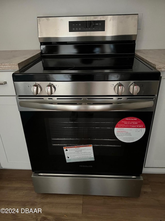 room details featuring white cabinetry, dark hardwood / wood-style flooring, and stainless steel range oven