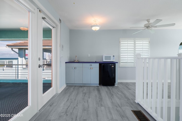 kitchen with refrigerator, sink, ceiling fan, light wood-type flooring, and black dishwasher