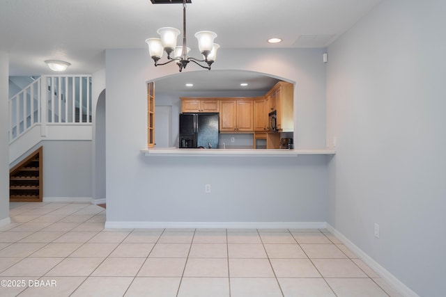 kitchen featuring black appliances, hanging light fixtures, light tile patterned floors, light brown cabinetry, and a chandelier