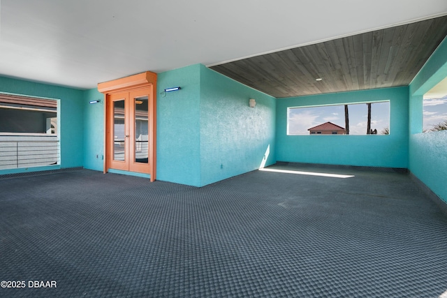 carpeted spare room featuring french doors and wooden ceiling