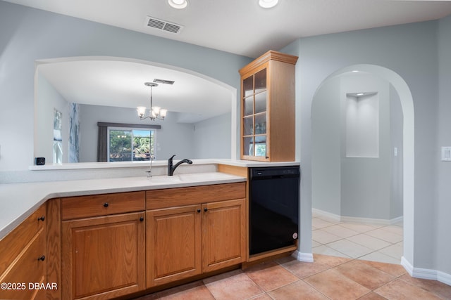 kitchen with pendant lighting, dishwasher, sink, light tile patterned floors, and a notable chandelier