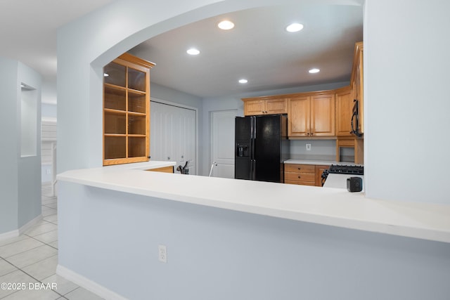 kitchen with kitchen peninsula, black fridge with ice dispenser, gas range, and light tile patterned floors