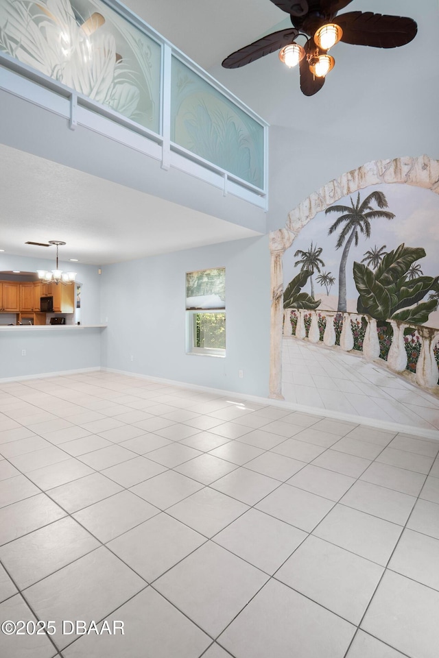 unfurnished living room with light tile patterned floors, a high ceiling, and ceiling fan with notable chandelier