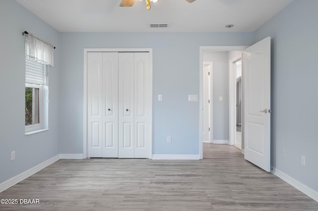 unfurnished bedroom featuring ceiling fan, a closet, and light wood-type flooring