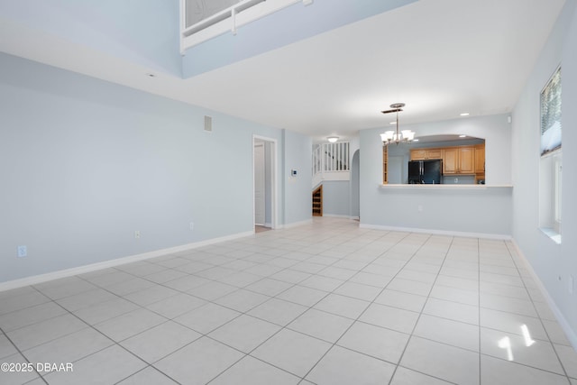 unfurnished living room featuring a notable chandelier and light tile patterned floors