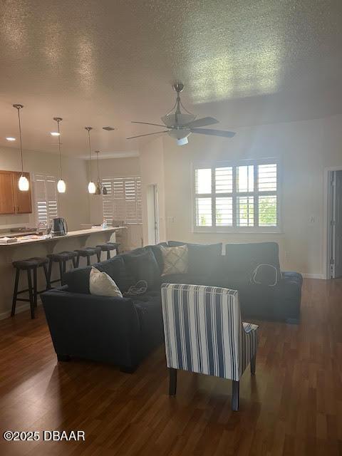 living room featuring a textured ceiling, ceiling fan, and dark wood-type flooring