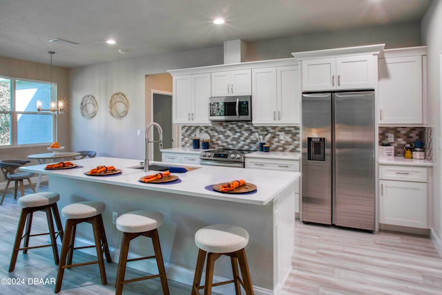 kitchen featuring white cabinets, appliances with stainless steel finishes, sink, and a kitchen island with sink