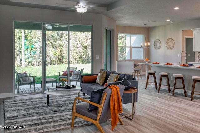 living room with ceiling fan with notable chandelier and light wood-type flooring