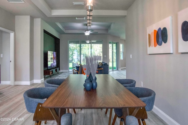 dining area featuring light hardwood / wood-style floors, ceiling fan, and a tray ceiling