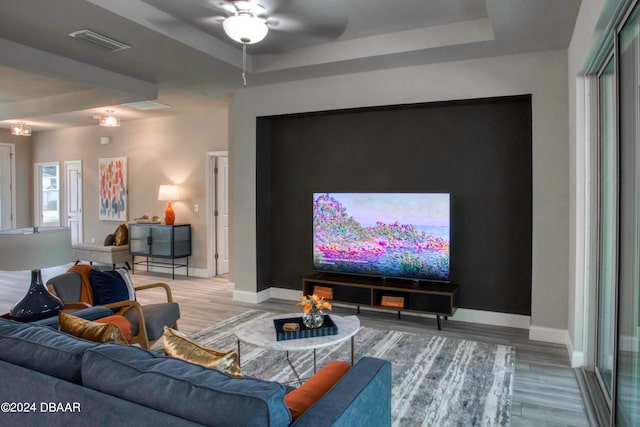 cinema room featuring hardwood / wood-style flooring, ceiling fan, and a raised ceiling