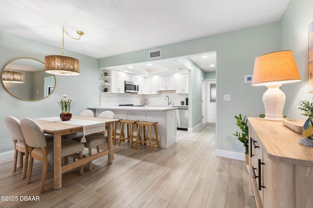 dining area with sink and light hardwood / wood-style flooring