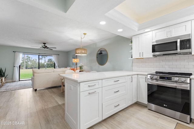 kitchen featuring white cabinets, tasteful backsplash, kitchen peninsula, pendant lighting, and appliances with stainless steel finishes