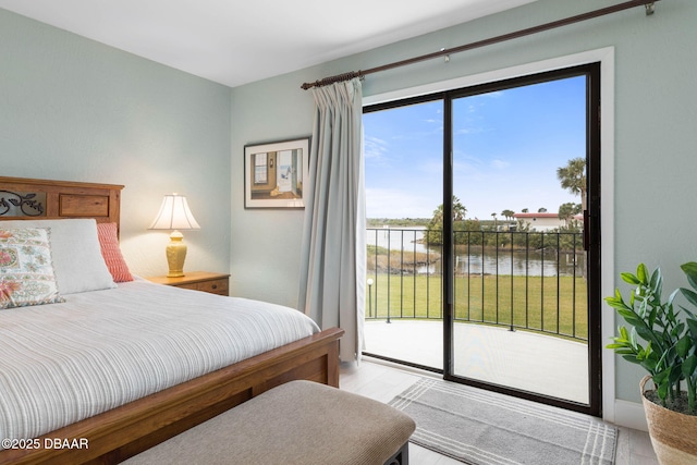 bedroom featuring light wood-type flooring, access to exterior, and a water view