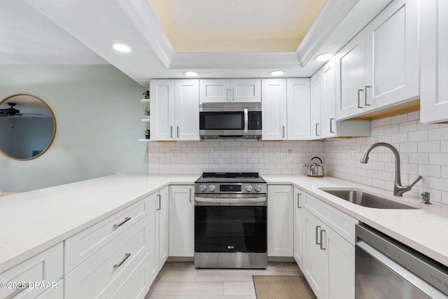 kitchen with stainless steel appliances, sink, white cabinets, a raised ceiling, and decorative backsplash