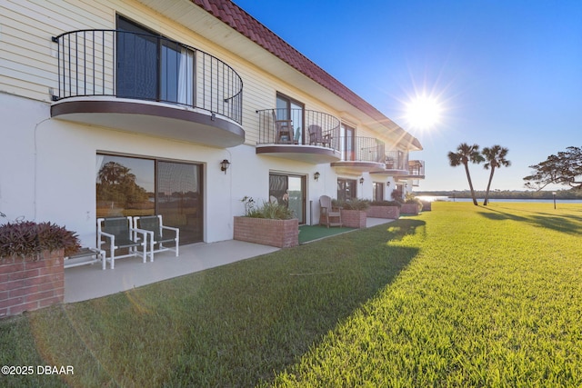 back of house with a balcony, a patio area, and a yard