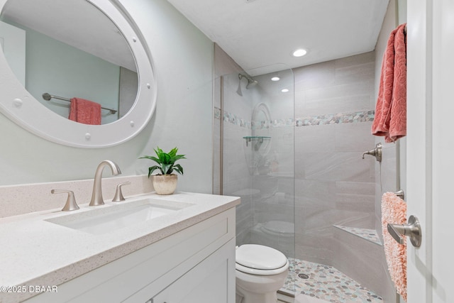 bathroom featuring toilet, a tile shower, and vanity