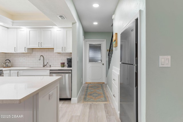 kitchen with stainless steel appliances, white cabinets, decorative backsplash, and sink