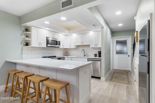 kitchen featuring a breakfast bar, stainless steel appliances, white cabinets, and sink