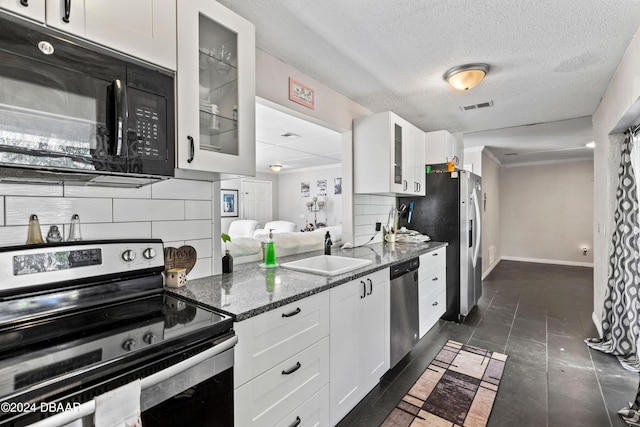 kitchen with stainless steel appliances, sink, dark stone counters, and white cabinets