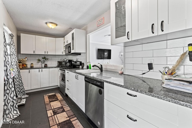 kitchen featuring white cabinetry, appliances with stainless steel finishes, dark tile patterned flooring, and a textured ceiling