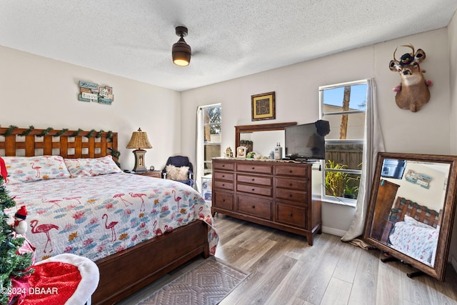 bedroom featuring ceiling fan, light hardwood / wood-style floors, and a textured ceiling